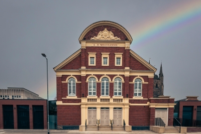 outside of an old theatre building with a rainbow in the sky
